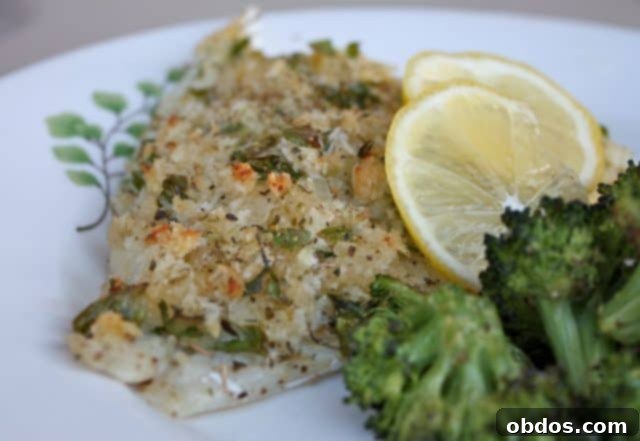 breaded and herbed baked fish on plate with broccoli and lemon
