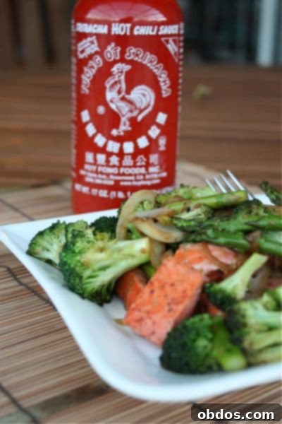 Πιάτο με σολομό και λαχανικά stir fry με ένα μπουκάλι καυτερή σάλτσα sriracha στο βάθος