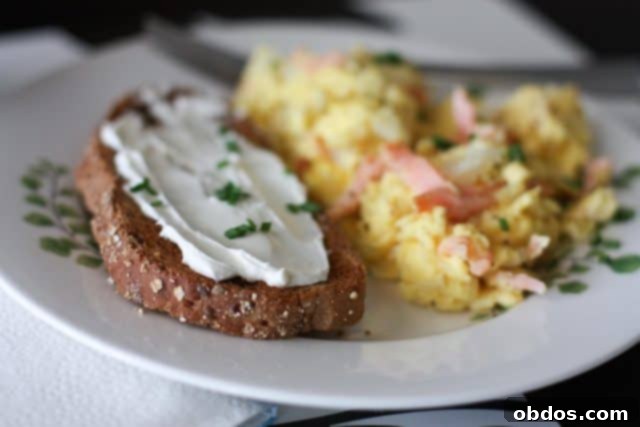 Κοντινό πλάνο σε αυγά scrambled με καπνιστό σολομό, με φρέσκα μυρωδικά, έτοιμα για σερβίρισμα.
