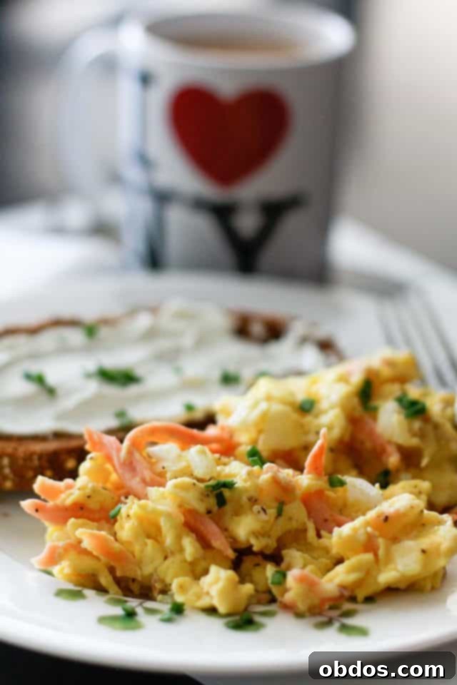 Πιάτο με αφράτα αυγά scrambled και κομμάτια καπνιστού σολομού, πασπαλισμένα με φρέσκο σχοινόπρασο, σερβιρισμένα με τοστ και τυρί κρέμα.