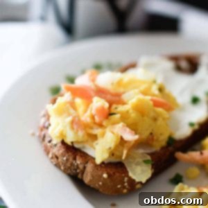 Τελικό πιάτο με αυγά scrambled και καπνιστό σολομό, γαρνιρισμένα με σχοινόπρασο και πιπέρι.