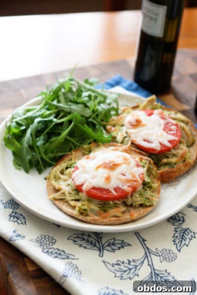 Πιάτο με δύο English muffins με ψιλοκομμένο κοτόπουλο, πέστο και ντομάτα, με λιωμένο τυρί μοτσαρέλα και μια πλευρά ρόκας